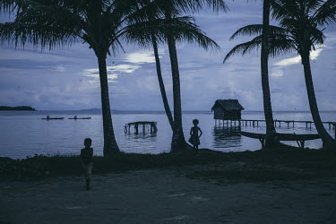 Children playing among palm trees on the shore of Mbunai village.
