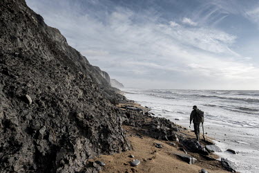 Fossil hunter Kameran Sabbaghi searches for fossils at the base of the cliffs on Charmouth beach, Dorset.