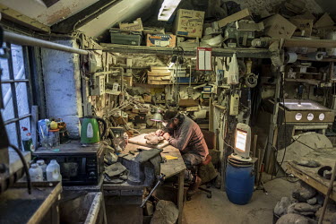 Veteran fossil collector Chris Moore chips away limestone to reveal a fossilised fish in his workshop in Charmouth. Moore has been collecting and preparing fossils for four decades, and his finds are...
