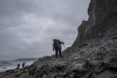 A fossil hunter walks over a recently fallen mudslide on Charmouth Beach.