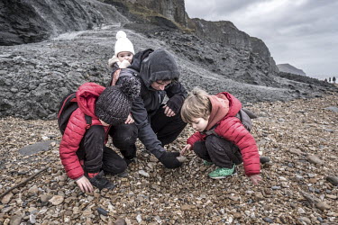 Fossil enthusiast Ross Jennings searches for ammonites in the gravel on Charmouth beach with his family.