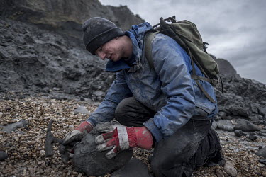 Fossil hunter Lee Bates breaks open a limestone nodule in search of fossils on Charmouth Beach.