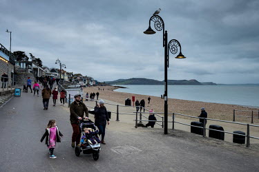 People walk along the seafront past street lights shaped like ammonites in Lyme Regis, Dorset. The town was the home of renowned fossil hunter Mary Anning, and is one of the most productive areas of E...