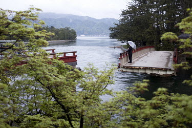 A man stands on the Kaisenkyou Rotating Bridge, which gives access to the sandbar at Miyazu Bay. This unusual bridge turns 90 degrees when ships pass through the waterway, and connects the Amanohashid...