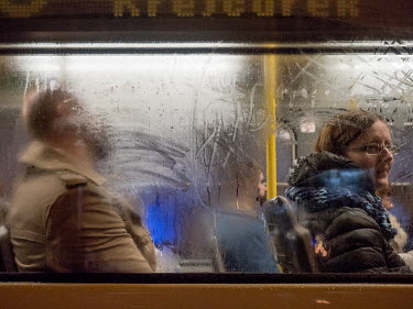 People seen through the window of an evening tram in Zizkov.