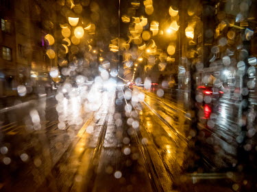 Rain drops obscure a window on an evening tram in Zizkov.