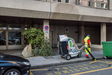 A street cleaner walks past a discarded Christmas tree on the street in Geneva.
