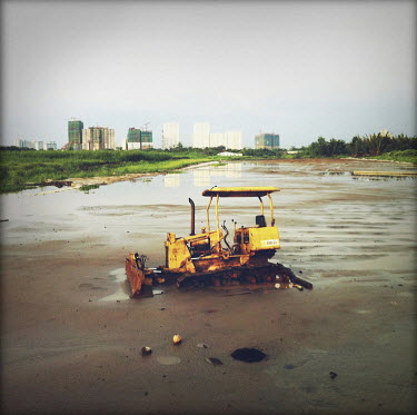 A bulldover abandoned in mud in an area which is planned for urban development.