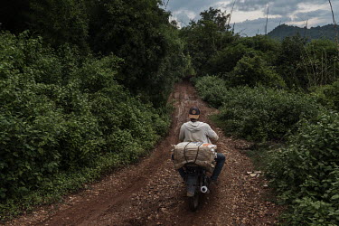 A miner carries sacks of ore down a mountain on his motorbike from a small-scale artisanal gold mine on the Indotan concession.