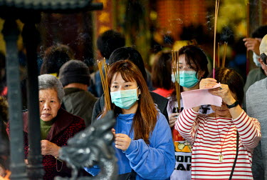 Members of the public wearing face masks against the possibility of catching the Wuhan Coronavirus as they pray at a temple.