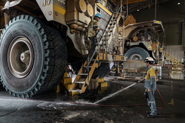 A worker sprays down a mining haul truck in a workshop at the Amman Minerals Batu Hijau mining concession.