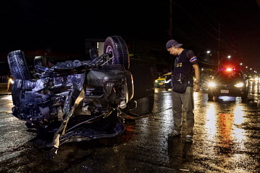 A paramedic looks at the wreck of a pickup truck that hit a lamp post and flipped over, injuring all five occupants. The paramedics thought the driver and passengers were drunk.
