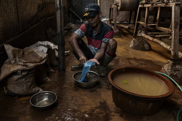 A worker looks at a small nugget, known as an amalgam, or mercury combined with gold, the end product after of processing ore at a ball mill where gold is extracted from ore mined in small-scale artis...