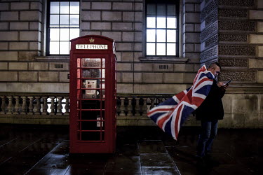 A man wrapped in a Union Jack flag uses his mobile phone in front of a K6 red telephone box, as he joins celebrations in central London to mark the United Kingdom leaving the EU.
