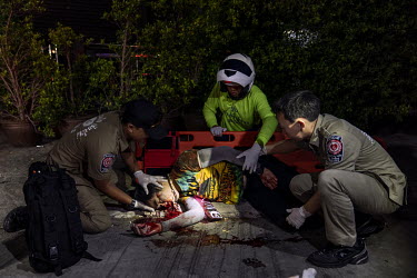 Paramedics treat a drunk man who was riding pillion when the driver, also drunk, crashed a motorbike during Songkran festivities, when there is a spike in traffic accidents.