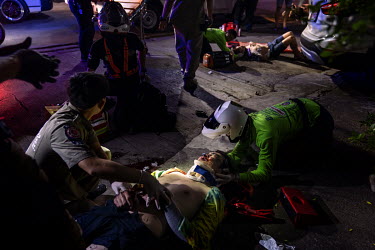 Paramedics treat a drunk pillion passenger and the drunk driver (background) who crashed their motorbike during Songkran festivities, when there is a spike in traffic accidents.