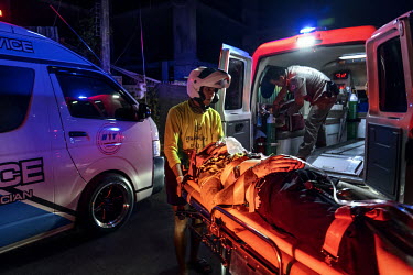 Paramedics treat a drunk man who was riding pillion when the driver, also drunk, crashed a motorbike during Songkran festivities, when there is a spike in traffic accidents.