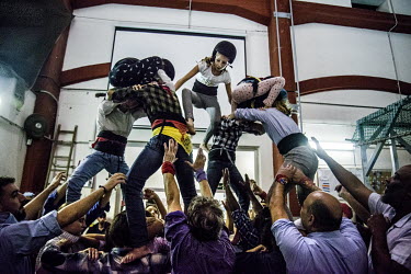 An 'anxaneta', the small child who acts as the top person of a human castle, 'casteller', climbs on top of a group of team mates during training ('assaig') at the 'Poblesec Castellers' club. 'Castelle...