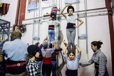 An 'anxaneta', the small child who acts as the top person of a human castle, 'casteller', climbs on top of a group of team mates during training ('assaig') at the 'Poblesec Castellers' club. 'Castelle...