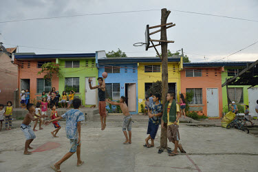 Youths play basketball on a court outside a row of colourful houses in a former slum district that was redeveloped via the 'Gawad Kalinga' poverty alleviation and nation-building movement.