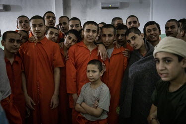 Young boys of various ethnicities stand together in a crowded and dark prison cell in north east Syria where they are being held as suspected ISIS members. Orphaned, or separated from their families,...