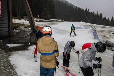 Skiers make their way in the rain at the bottom of one of the ski runs leading down to the base of the 1800m Avoriaz ski resort. At this lower level this snow is produced by snow cannons, when the wea...