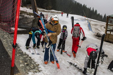Skiers make their way in the rain at the bottom of one of the ski runs leading down to the base of the 1800m Avoriaz ski resort. At this lower level this snow is produced by snow cannons, when the wea...