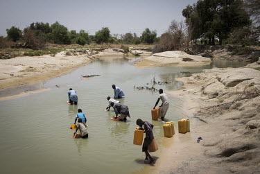 People collecting water from the Komadougou Yobe River which forms a natural border between Nigeria and Niger.