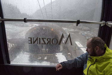 A skier looking out of a rain-lashed window from a cable car, rising up to the slopes of Avoriaz ski resort, which at 1800 metres is less exposed to lack of snow than many other resorts although even...