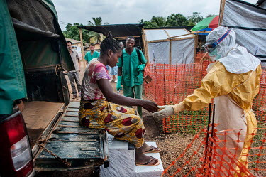 Finda Marie Kamano (33) is helped from the back of an MSF vehicle by a health worker dressed in full personal protective equipment (PPE) at the Ebola Treatment Centre (CTE). She was brought from her h...