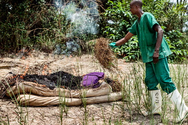 A health worker with an MSF team burns a mattress taken from the home of a woman who has been diagnosed with Ebola, as everything that cannot be disinfected with chlorine must be burned.