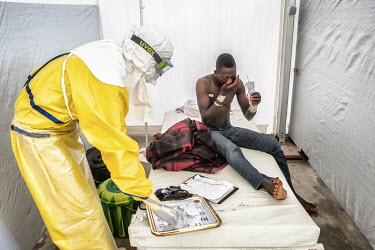 A nurse in full personal protective equipment (PPE) attends to Adama Kourouma (20) who arrived at the Ebola Treatment Centre (CTE) with bleeding gums one of the classic symptoms of Ebola, although he...
