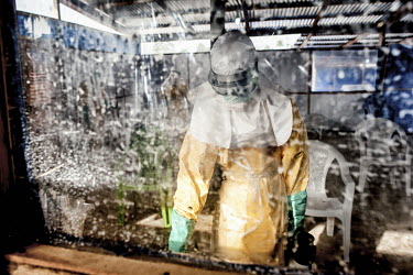 A staff member, dressed in full personal protective equipment (PPE), who is responsible for hygiene at the facility sprays disinfectant onto surfaces in the triage area at the Ebola Treatment Centre (...