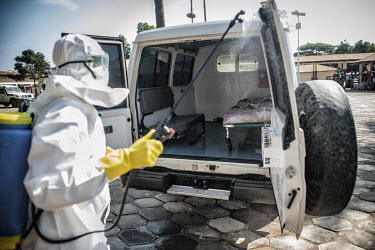 A worker at an Ebola Treatment Centre (CTE) wearing full personal protective equipment (PPE) sprays an ambulance with disinfectant.