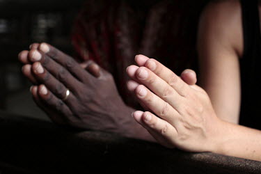 A black man and a white woman praying together in a church.