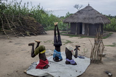 Henry Malish (13) and two of his friends practice headstands on a patch of land outside the house where his mother, Angelina Monday, lives with her six children.   The family crossed the border from w...