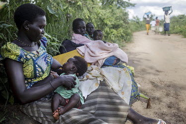 Angelina Monday (30, left) breastfeeding her daughter Lillias Sadia, who is less than six months old, as she rests along with her six children and other relatives who have finally reached Uganda after...