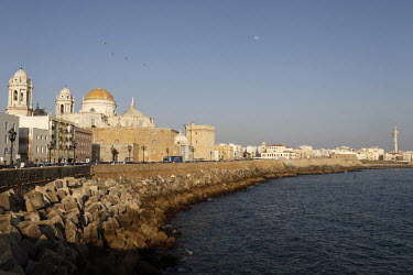 The moon visible during the day sky over the Cadiz waterfront.