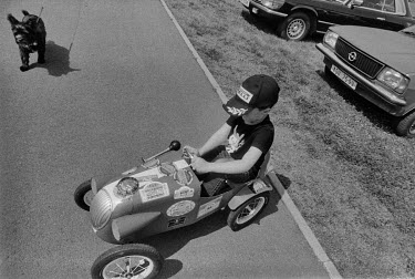 A boy rides on a toy racing car during veteran car show organized by Dobrichovice Veteran Car Club.