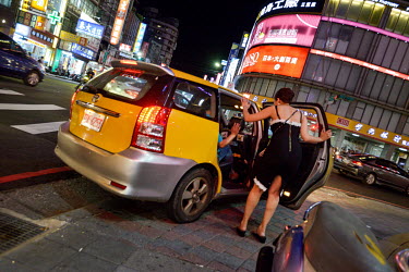 A hostess from a Sanchong 'Love Hotel' sees off a client in his taxi.