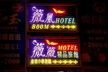 An illuminated neon sign indicating the location of a 'Love Motel' where rooms can be rented on an hourly basis.