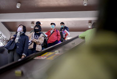 Passengers wearing face masks against the COVID-19 virus ride escaltor into Longshan Temple MRT station.
