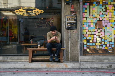 An employee uses his mobile phone during a break from his work at the popular Hong Kong-style Gung Lok cafe on Chifeng Street. The venue openly supports the Hong Kong pro-democracy demonstrations and...