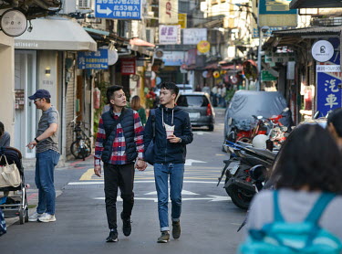 A male couple stroll hand-in-hand along Chifeng Street.