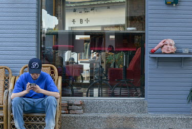 A man sits on the free seating offered outside the Resto-Bar on Chifeng Street.