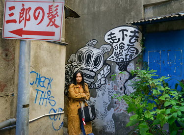 A woman emerges from a very narrow alleyway, lined with grafitti, that leads off Chifeng Street.