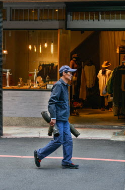 An engineering worker carries sections of piping past a fashion store on Chifeng Street.