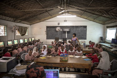Students and their teacher in a computer equipped classroom at Mwijabu Primary school where a digital learning project is helping young students to work with new, interactive multimedia software that,...