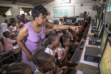 Students and their teacher in a computer equipped classroom at Mwijabu Primary school where a digital learning project is helping young students to work with new, interactive multimedia software that,...