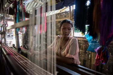 A Kachin woman displaced by fighting in northern Myanmar works at a loom in the Palala IDP camp.
